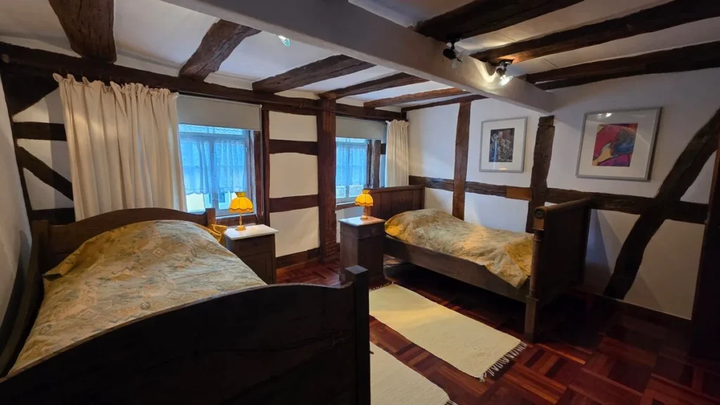 Schlafzimmer mit zwei Betten unter altem Fachwerk