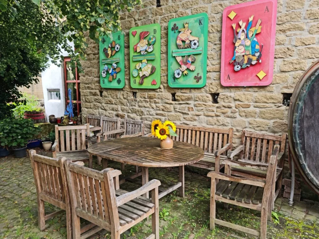 Gartentisch vor der Bruchsteinmauer mit Kunstwerken