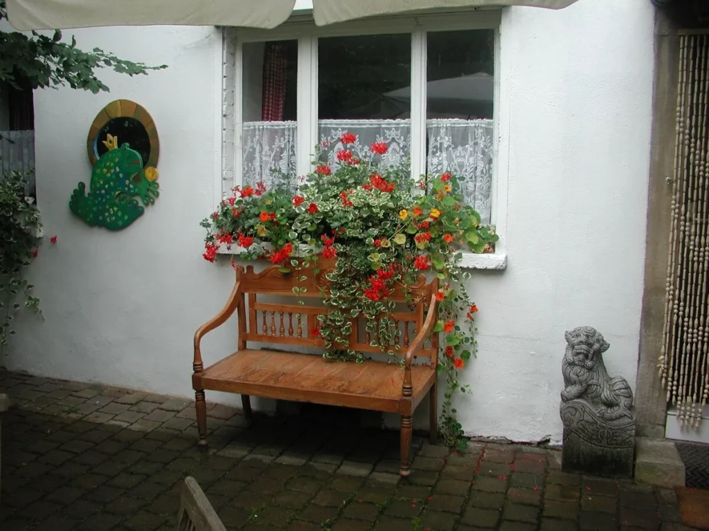 Bank mit Geranien an der Hauswand